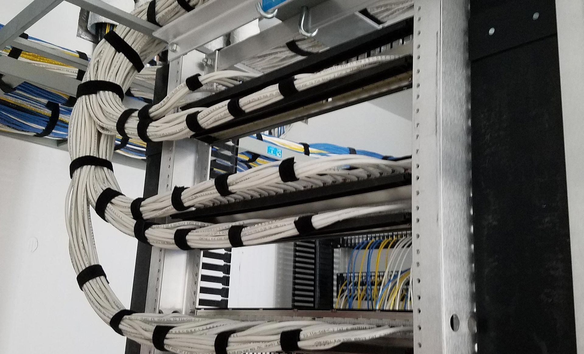 A bunch of wires are hanging from a rack in a server room.