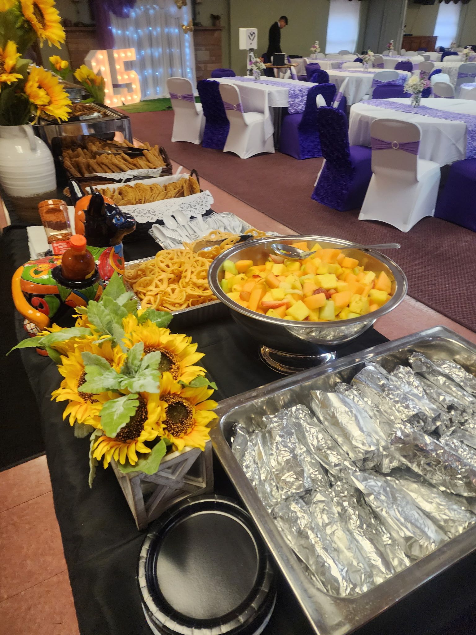 A buffet table with a variety of food and flowers on it.