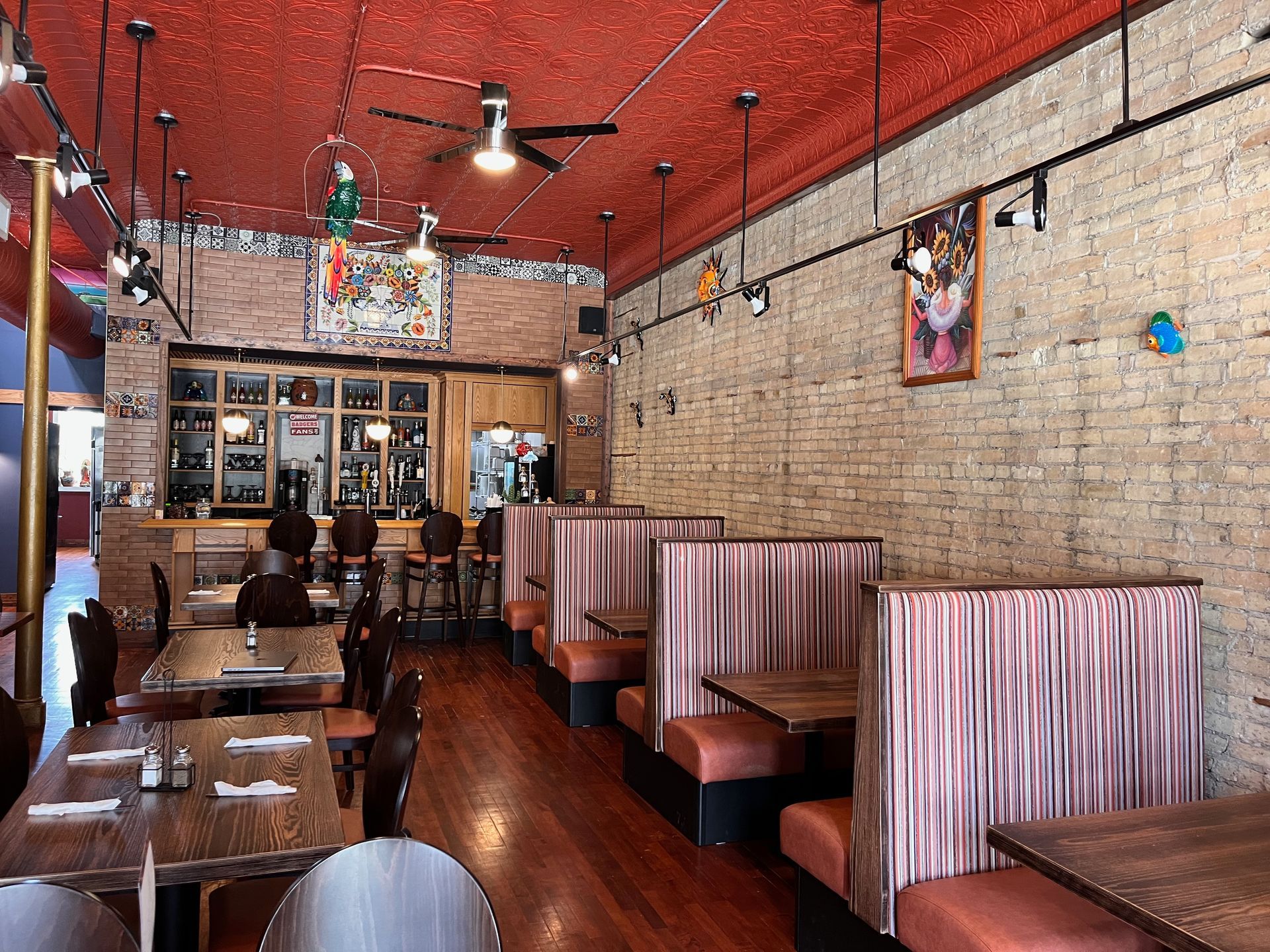 A restaurant with tables and booths and a red ceiling.