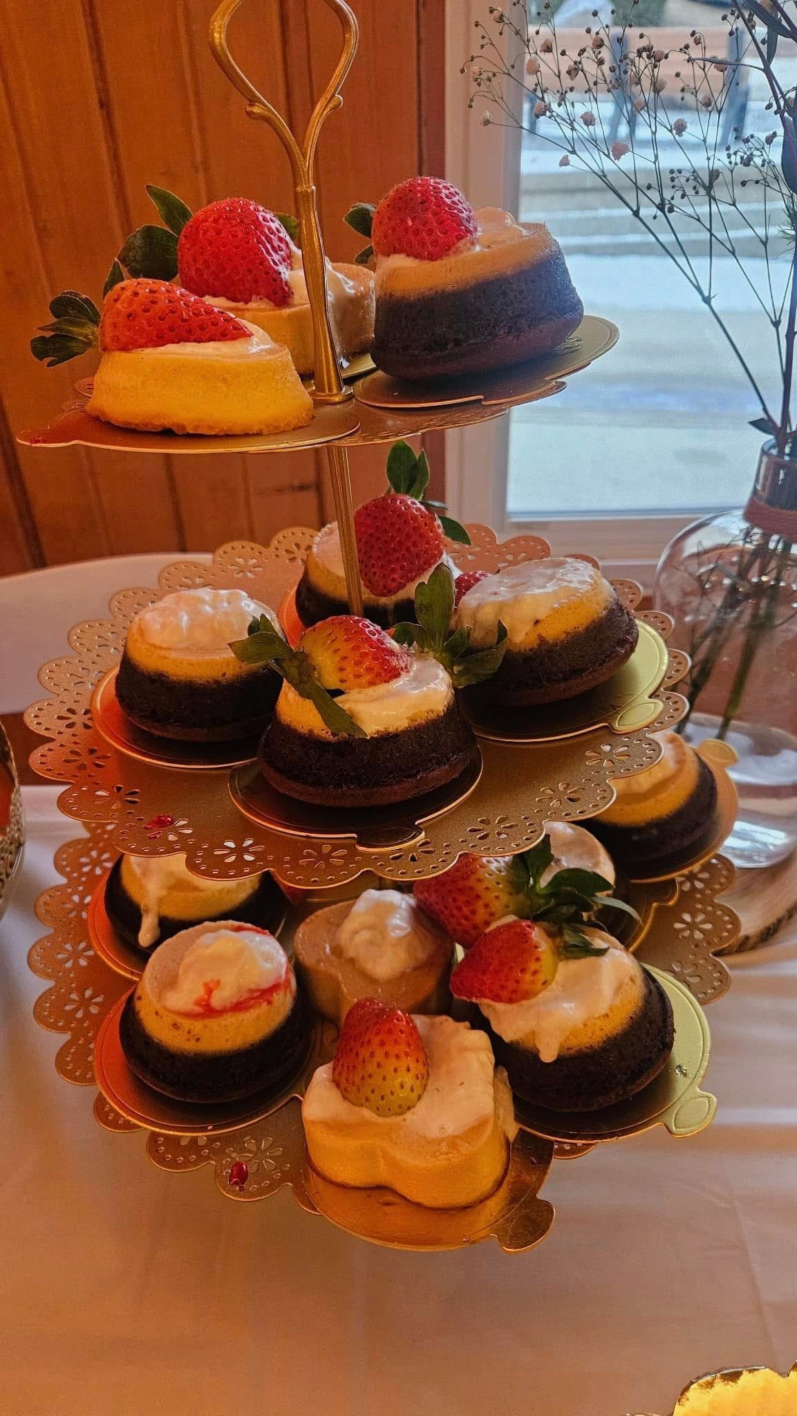 A cupcake stand filled with cupcakes and strawberries on a table.