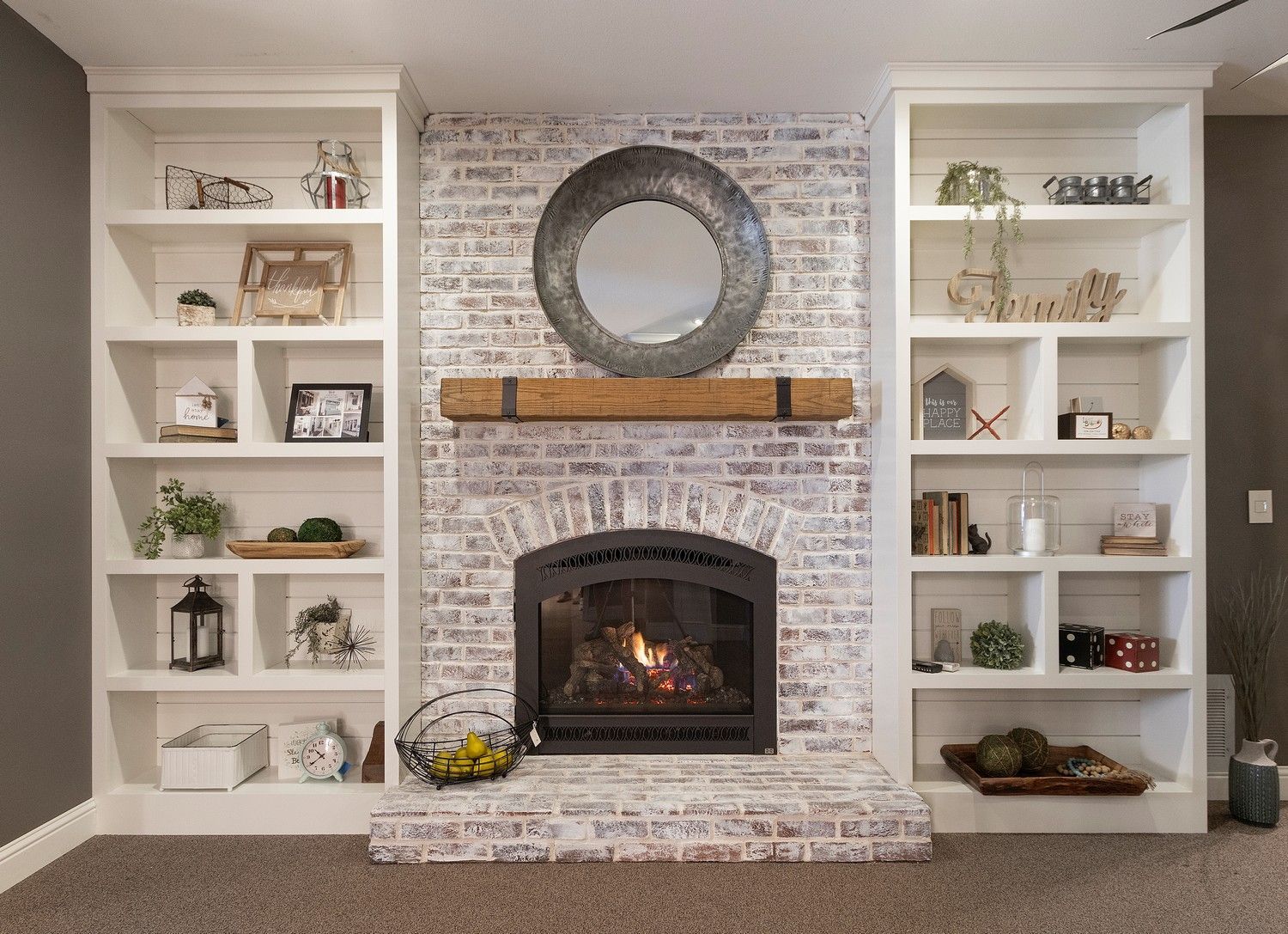 Elegant living room fireplace with brick surround, wreath above, and built-in shelves on both sides.