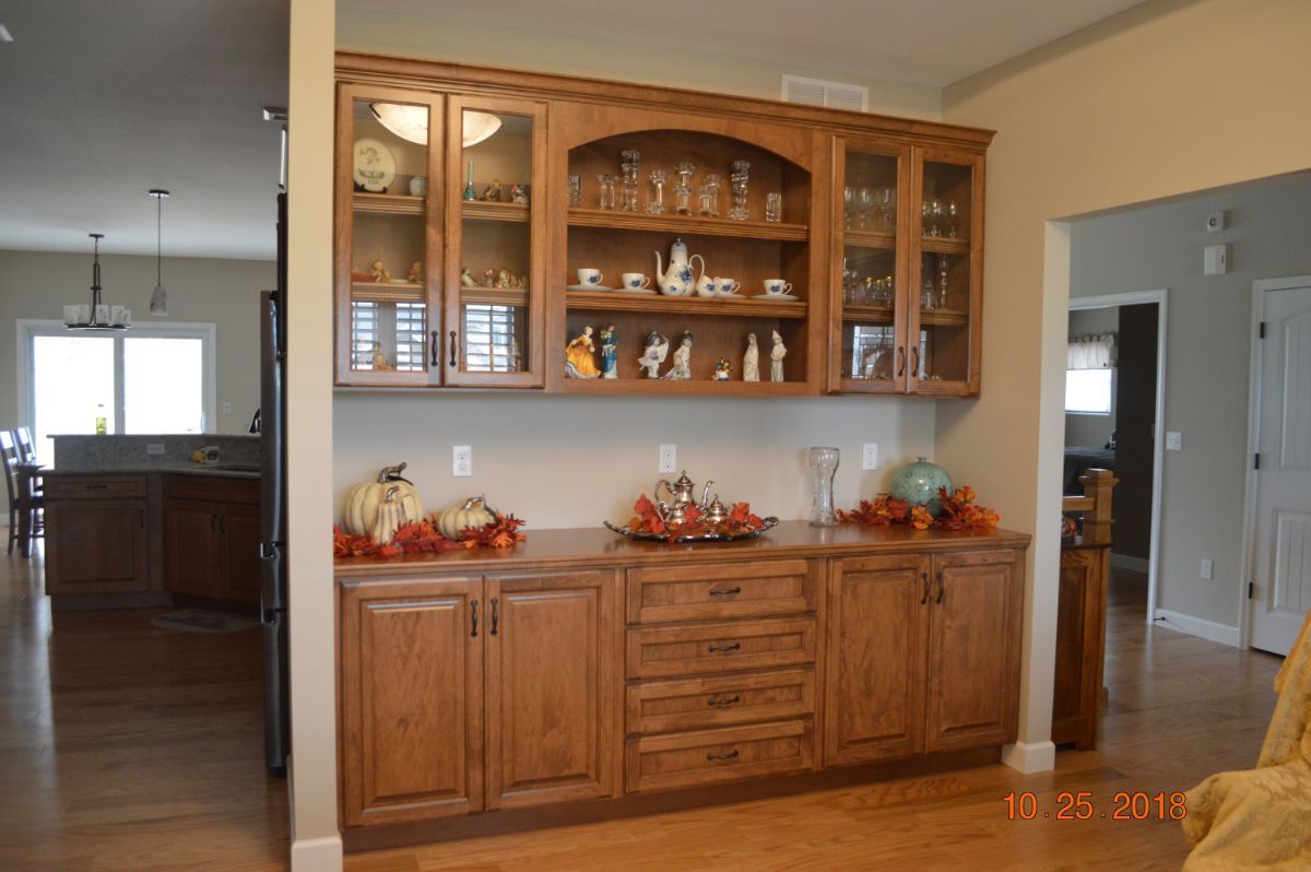 Wooden china cabinet with glass doors and fall decor in a dining room
