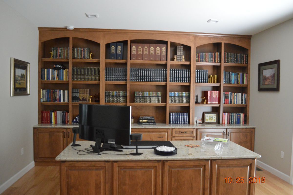 Wooden home office with built-in bookshelves, computer monitor, and desk.