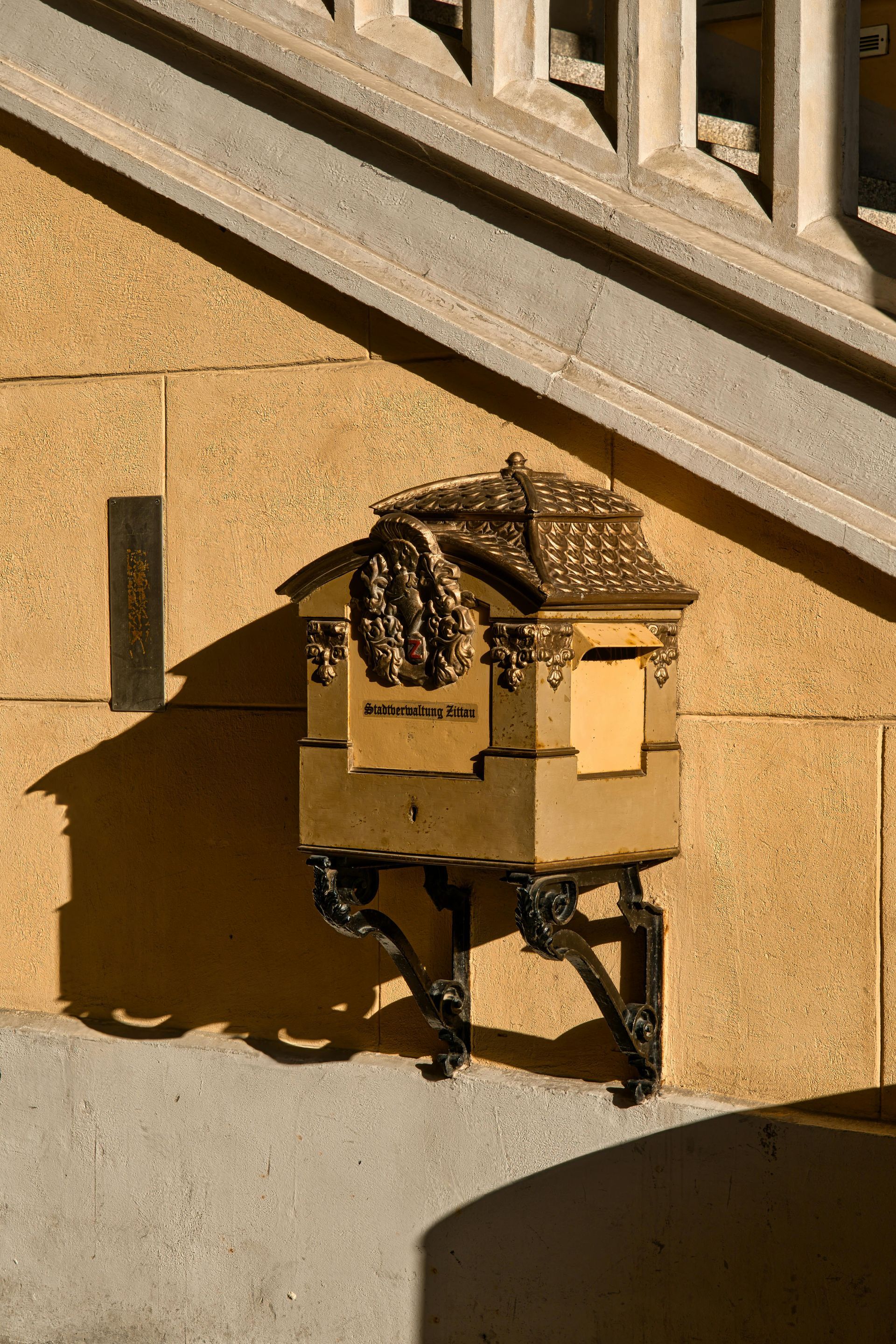 Cardboard box on a small robot in sunlight beside a stone wall and stairs