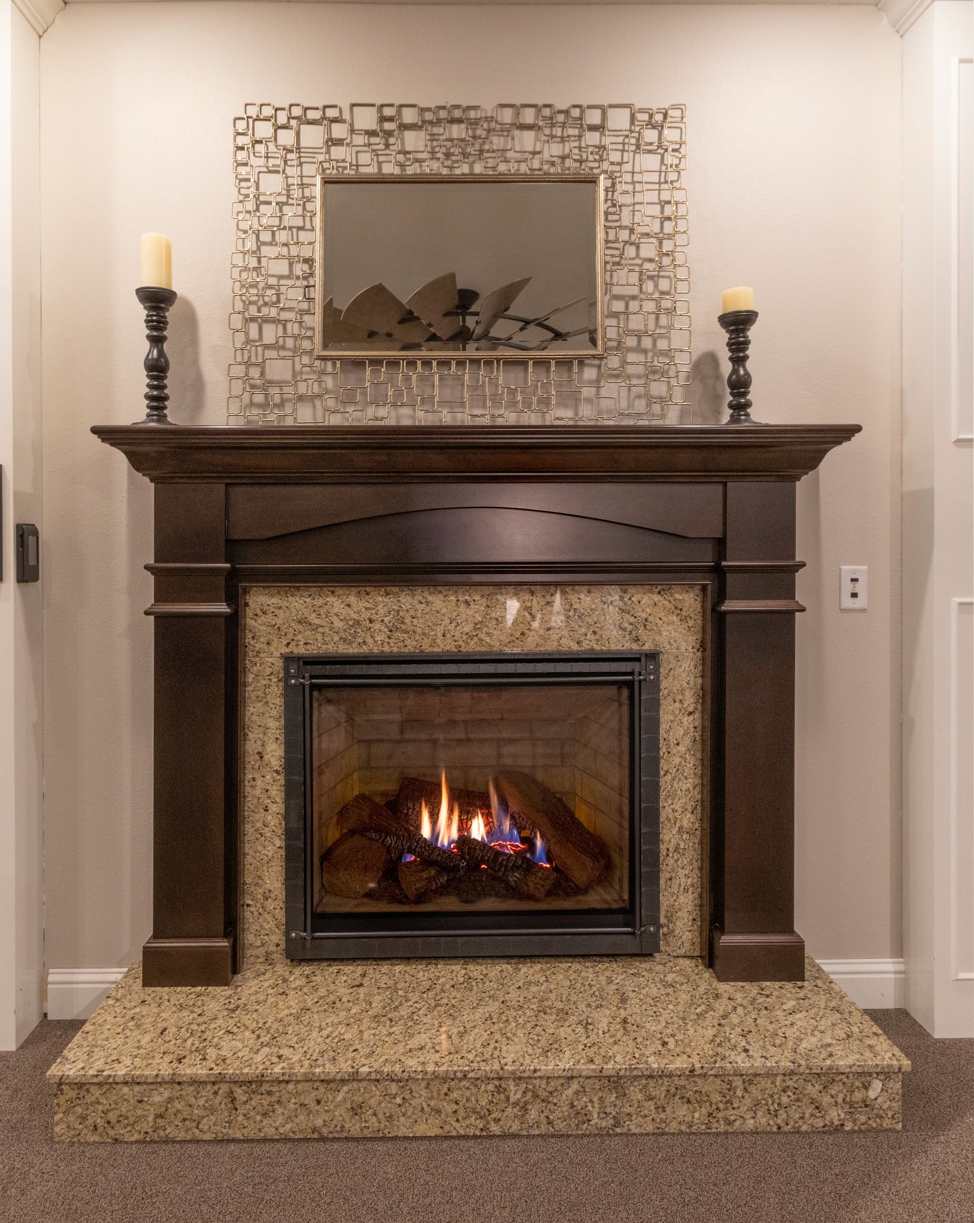Elegant living room fireplace with dark wood mantel, stone surround, and a small fire burning.