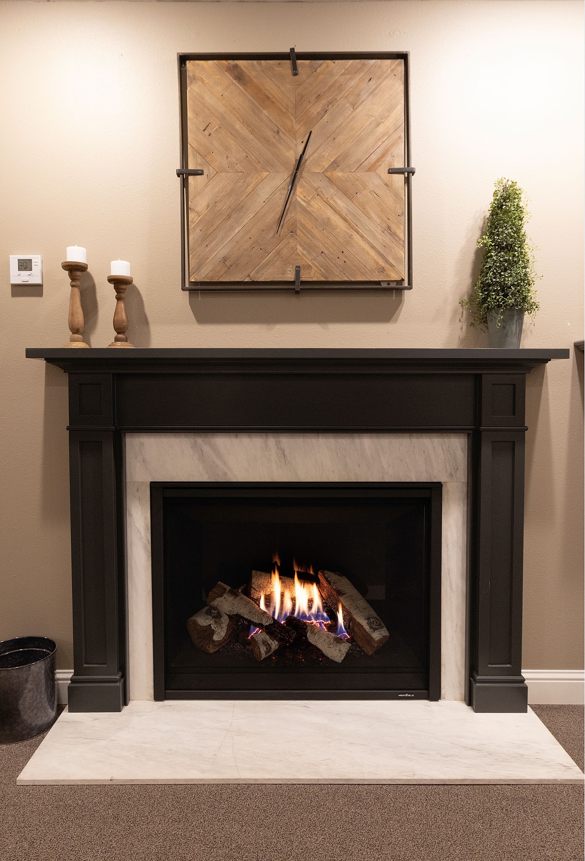 Modern fireplace with black mantel, lit fire, wall art above, and small decor pieces on either side