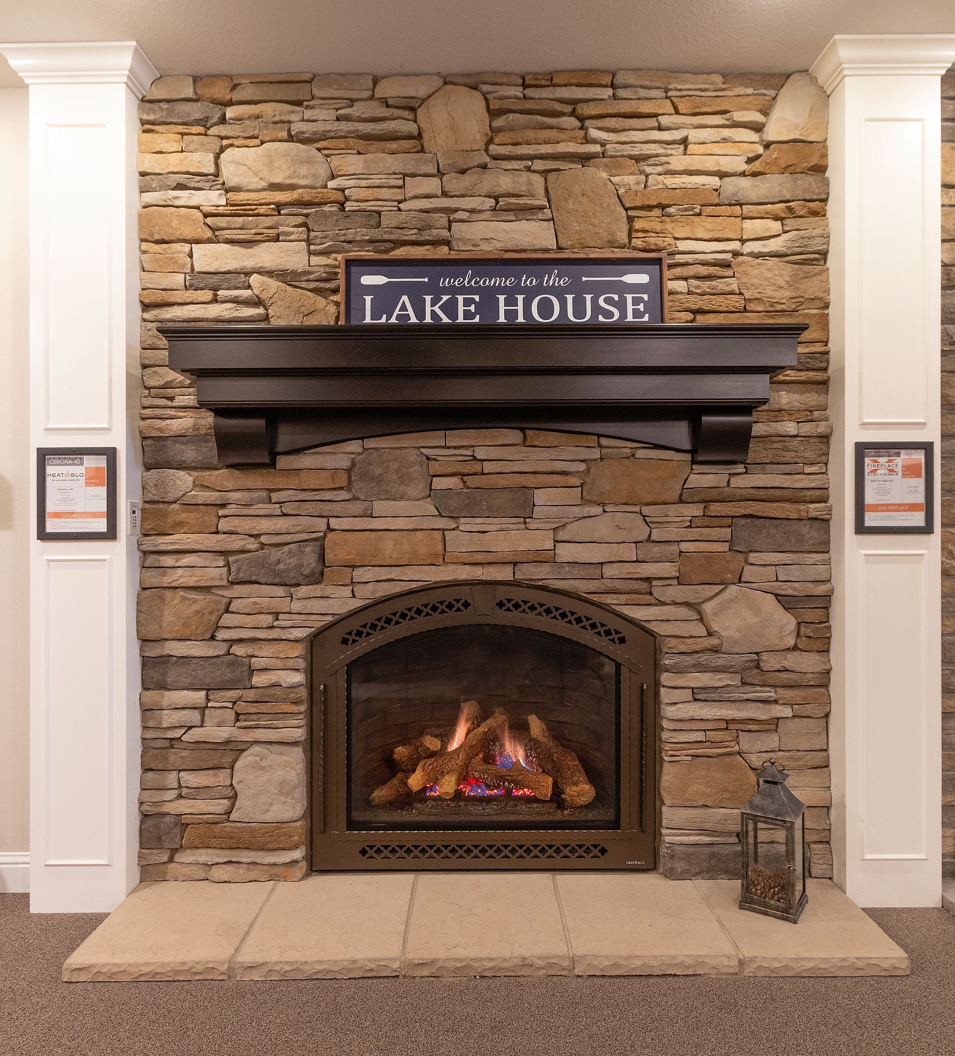 Stone fireplace with lit fire and “Lake House” sign in a cozy interior room