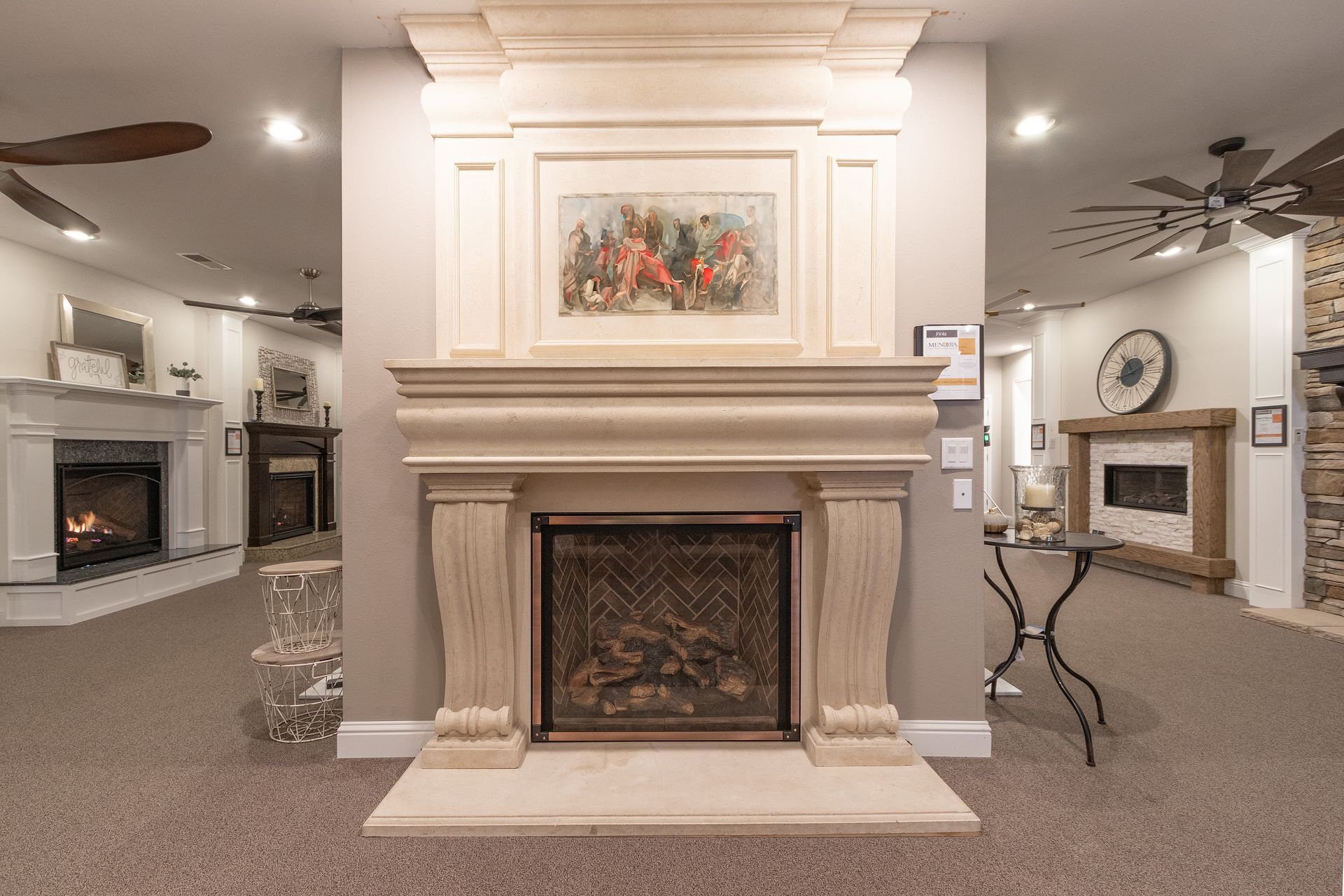 Elegant showroom with a central stone fireplace, carpeted floor, and framed artwork above the mantel.
