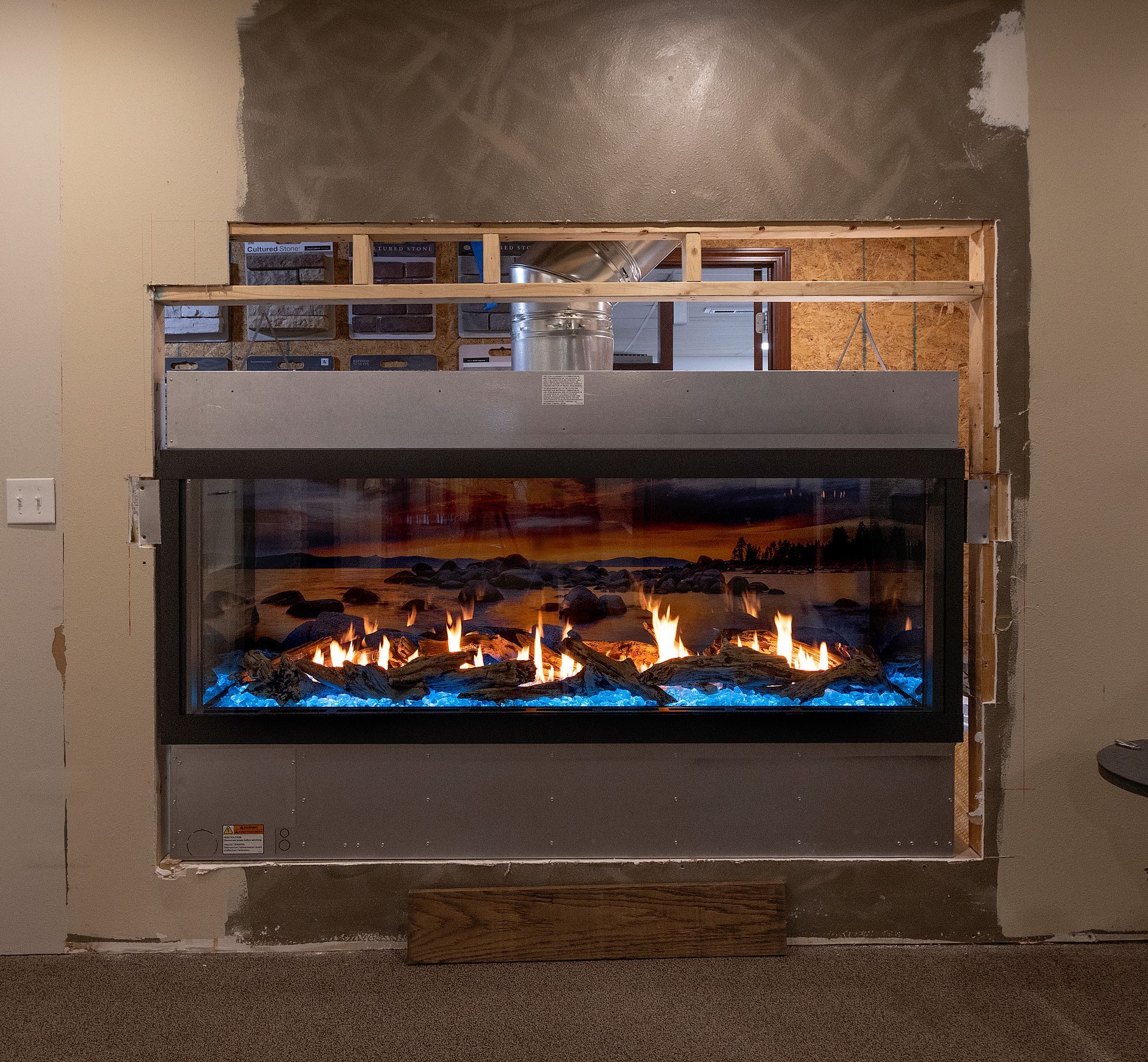 Built-in modern fireplace with blue flames beneath a gray unfinished wall opening