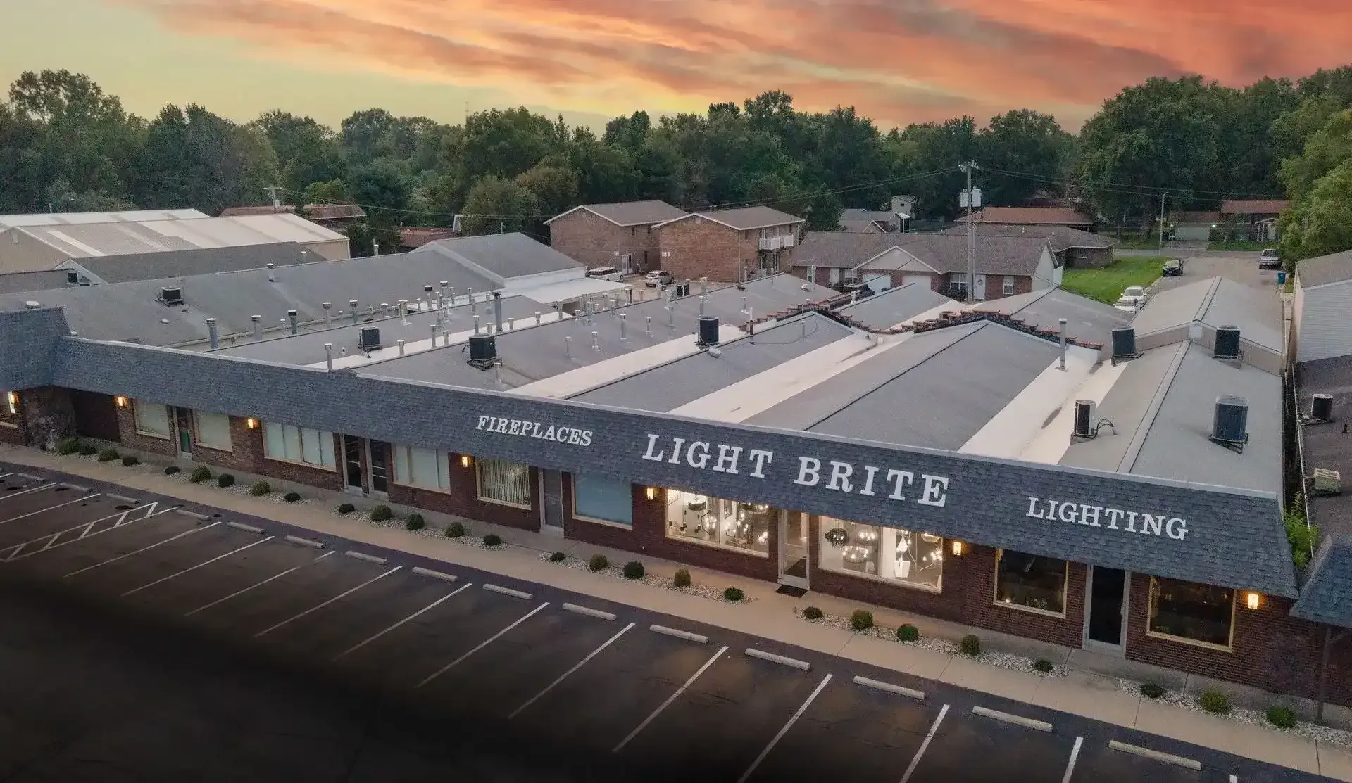 Aerial view of Light Street Living apartment building at sunset with parking lot and trees