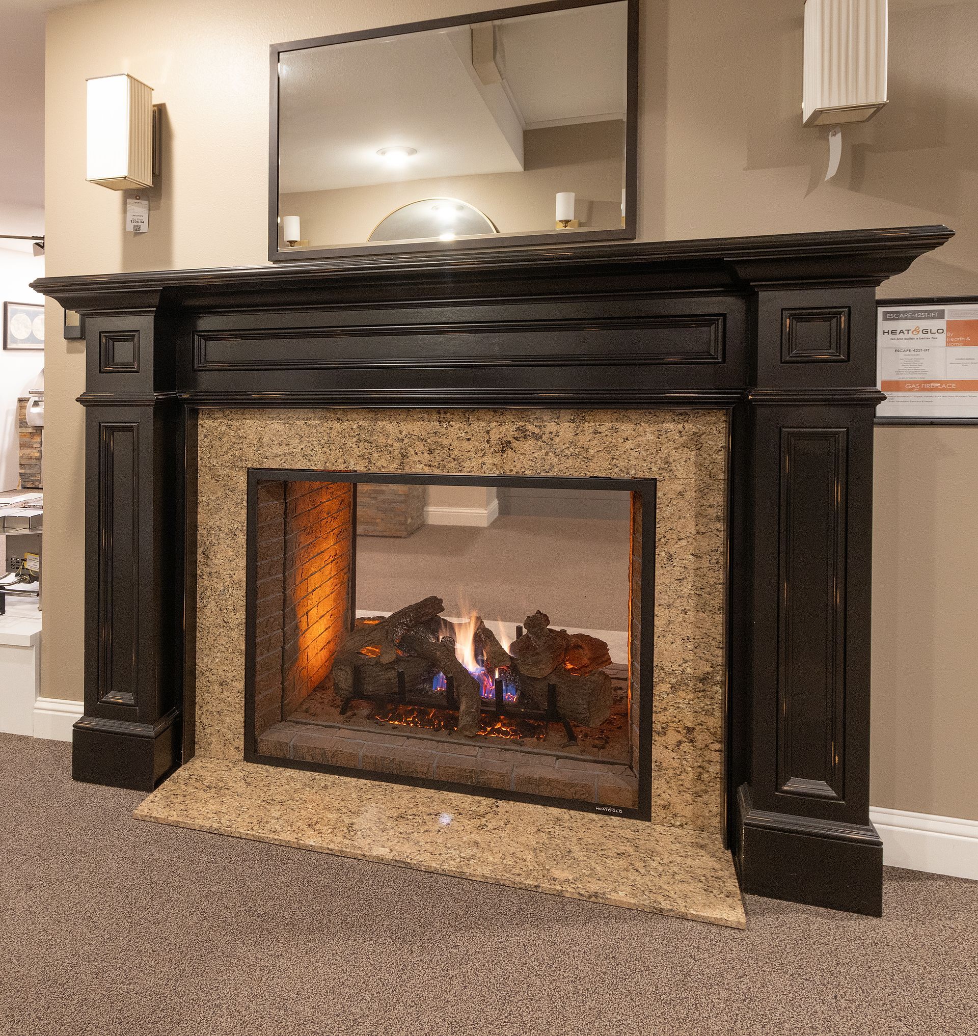 Lit fireplace with dark wood mantel and mirror in a carpeted room