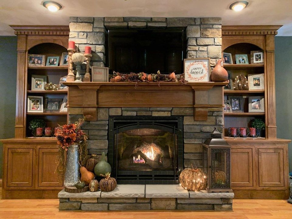Cozy living room fireplace with stone surround, wood mantel, and built-in bookshelves on both sides