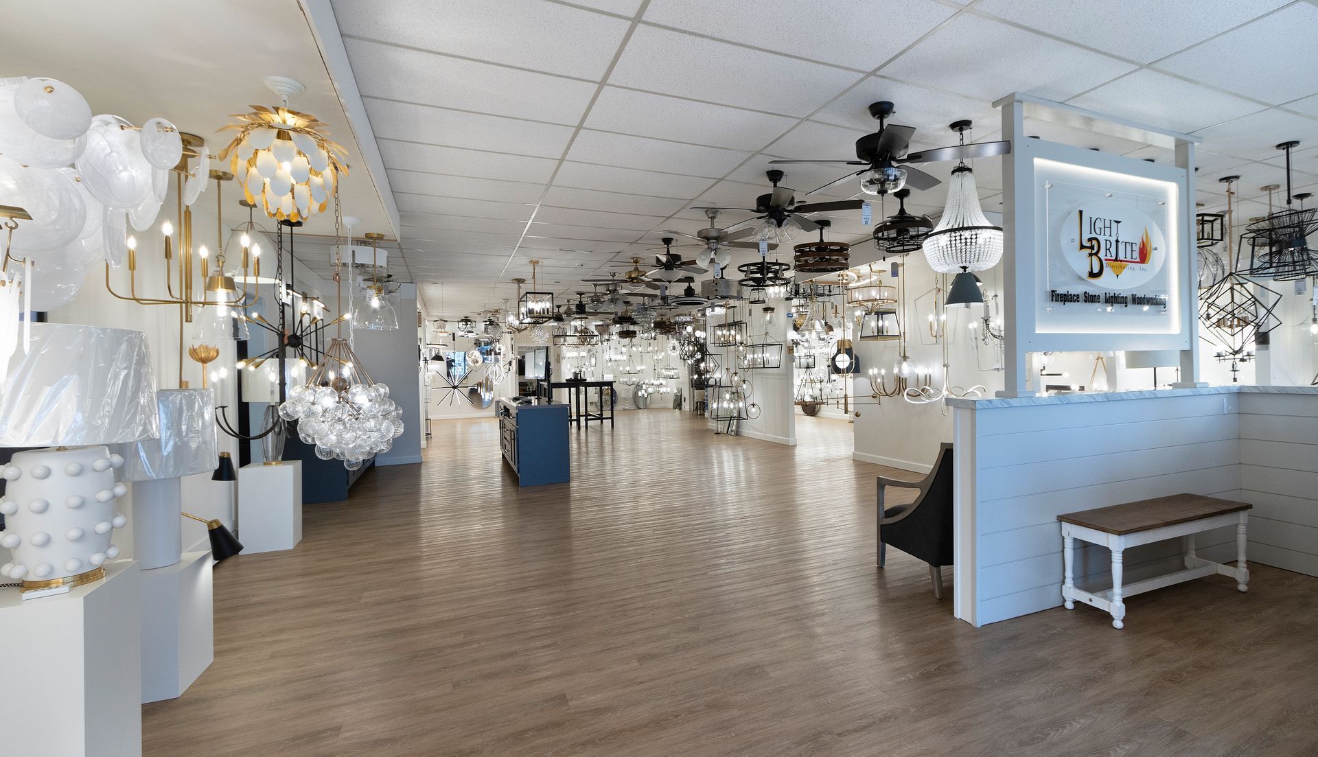 Bright lighting showroom with hanging chandeliers and lamps displayed along a spacious, tiled floor.