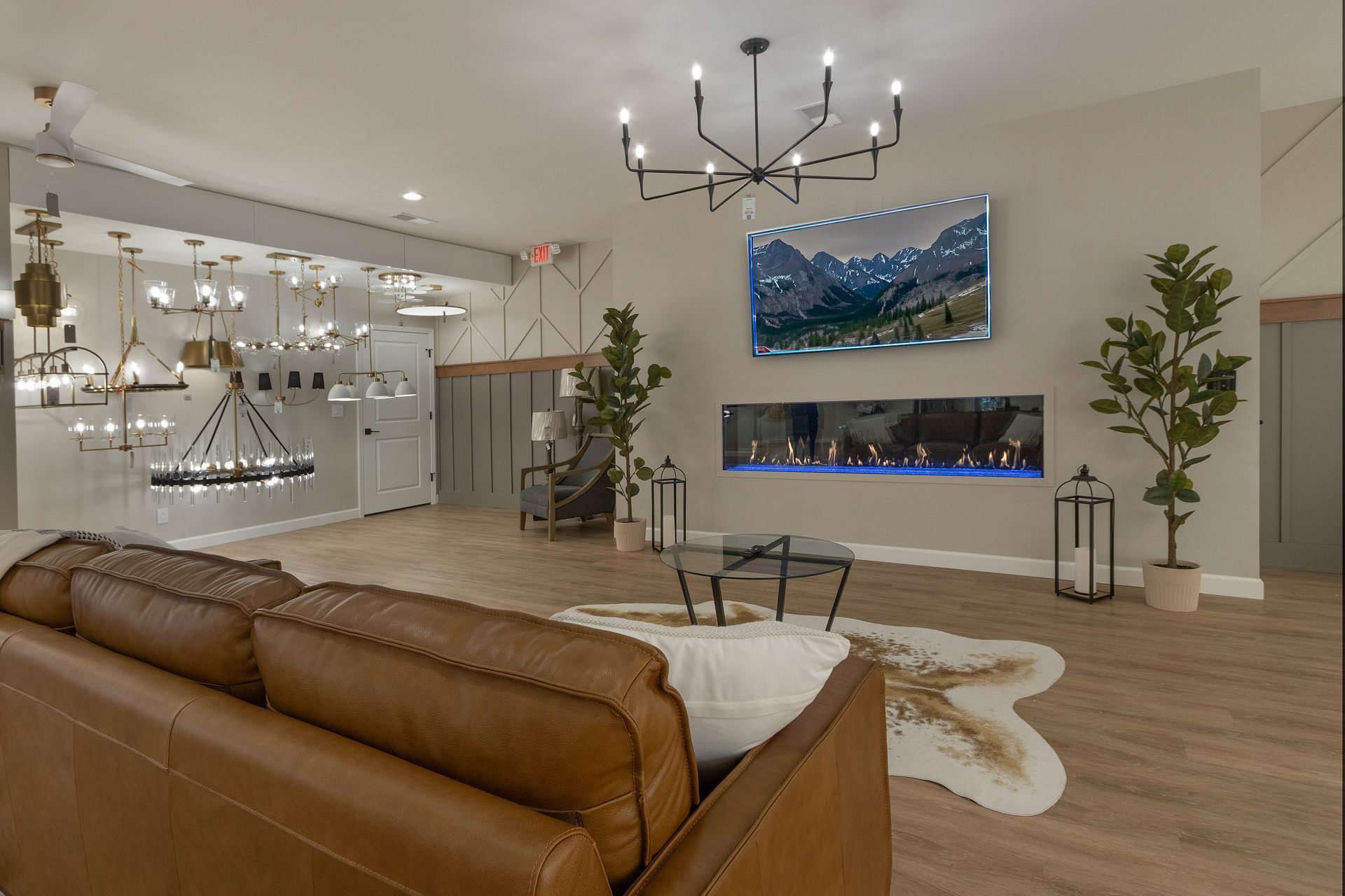 Modern living room with brown leather sofa, fireplace, chandelier, and wall-mounted TV over a mantel