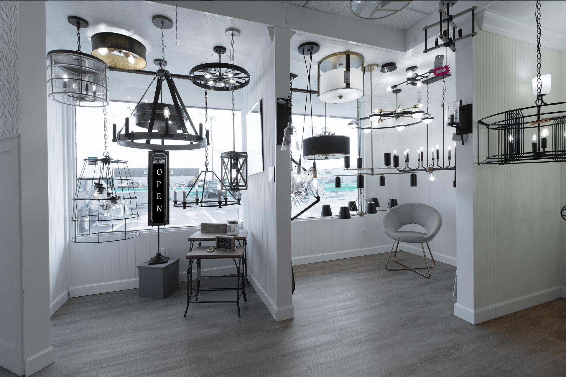 Modern showroom with hanging light fixtures, white walls, and minimalist furniture displayed on wood flooring