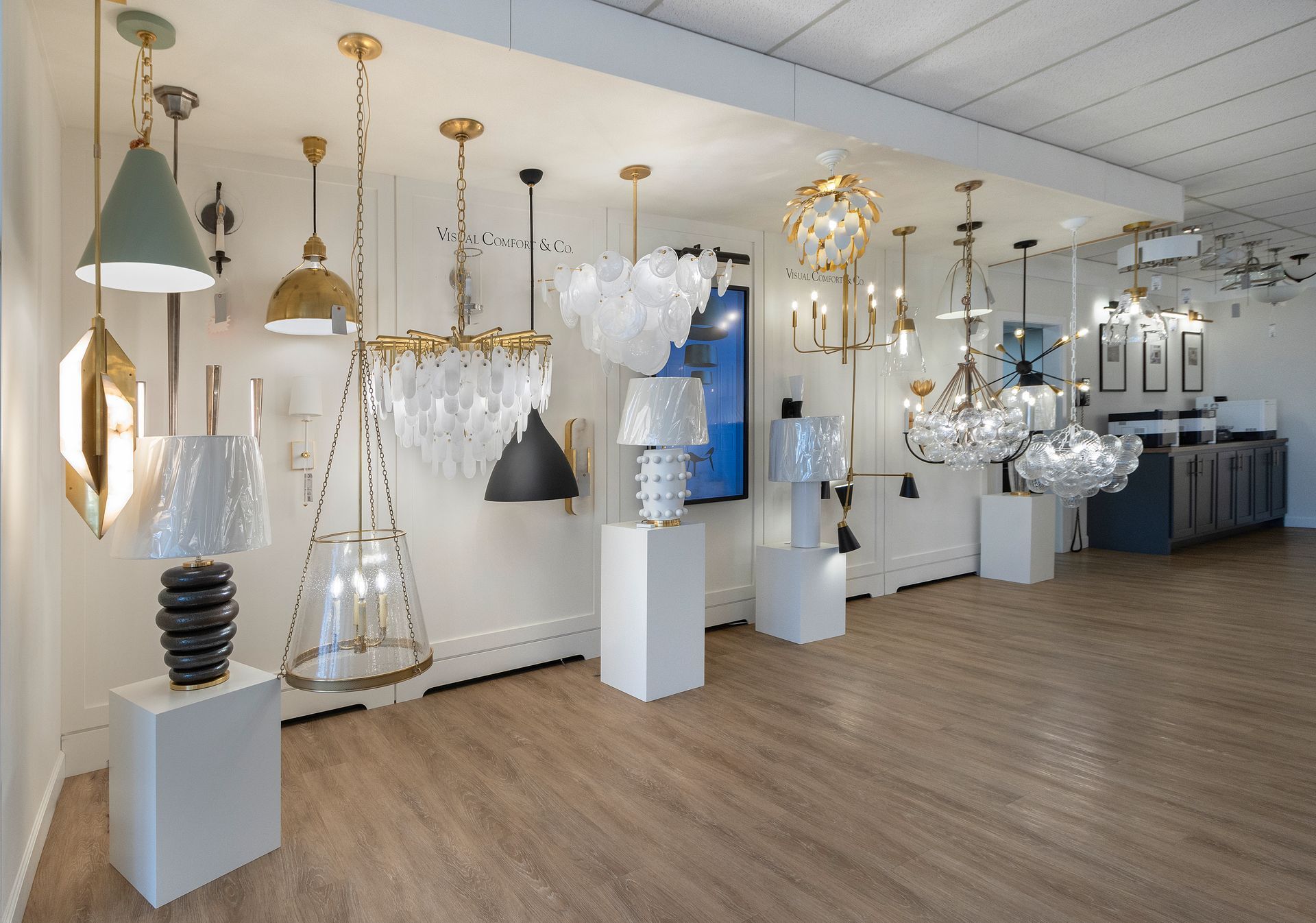 Lighting showroom with hanging pendant lamps and chandeliers displayed in a bright white interior