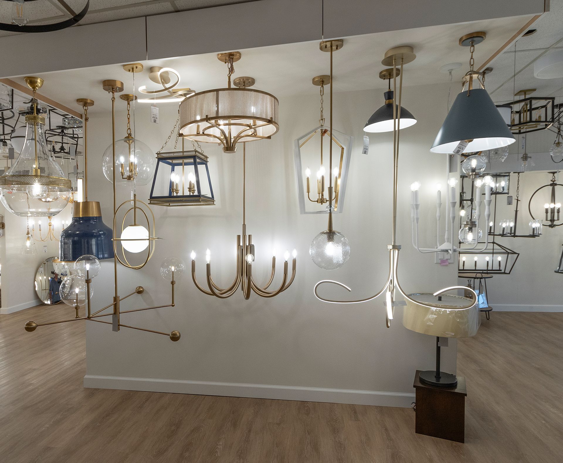 Assorted hanging chandeliers and pendant lights displayed in a lighting showroom.