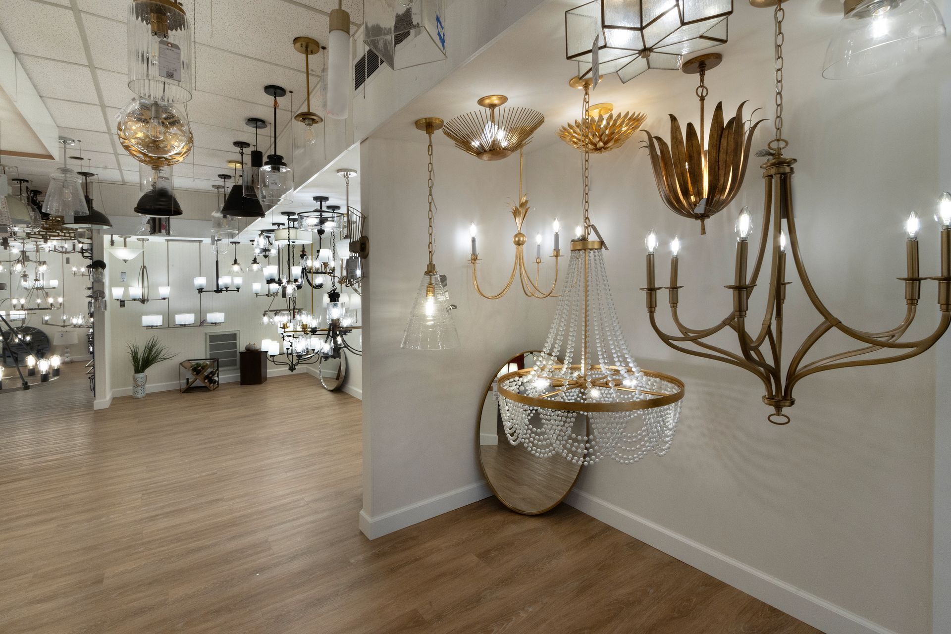 Lighting showroom with ornate chandeliers and wall sconces in a bright, modern display space