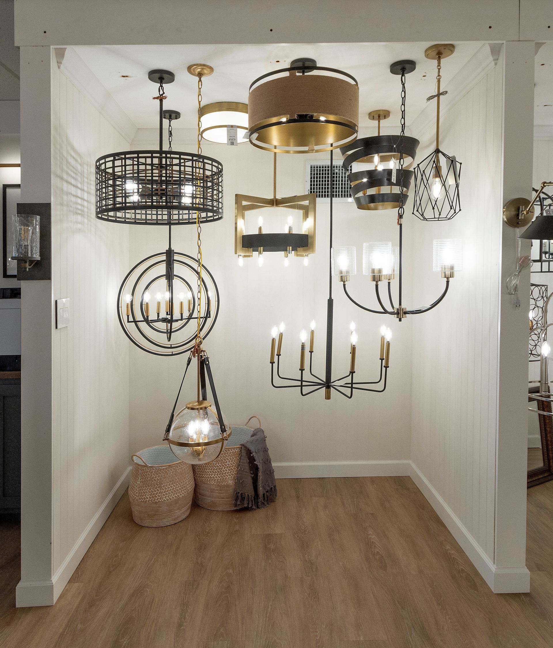 Assorted decorative pendant lights hanging in a showroom display with woven baskets on the floor.
