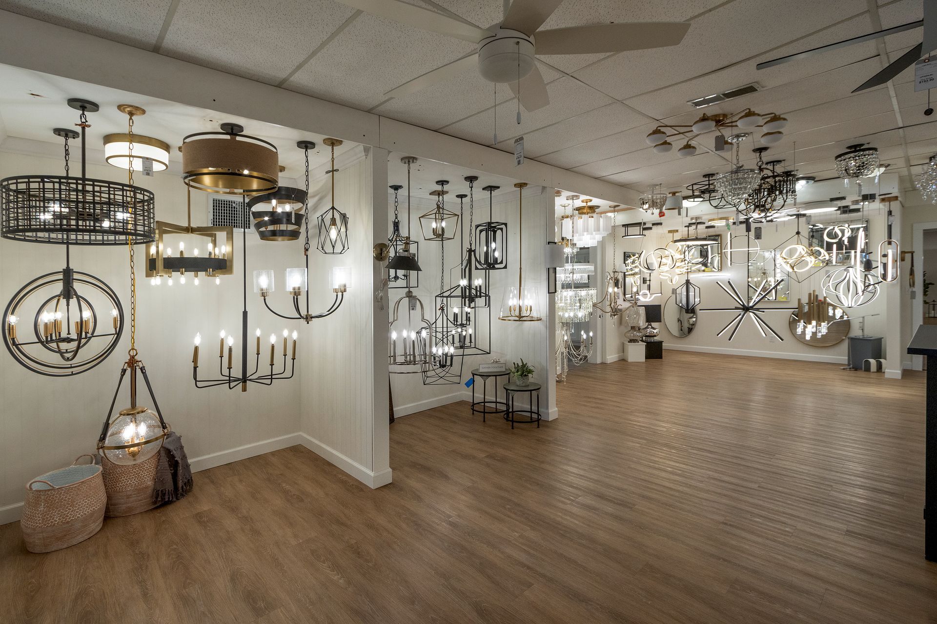 Showroom filled with hanging chandeliers and modern light fixtures over wood flooring