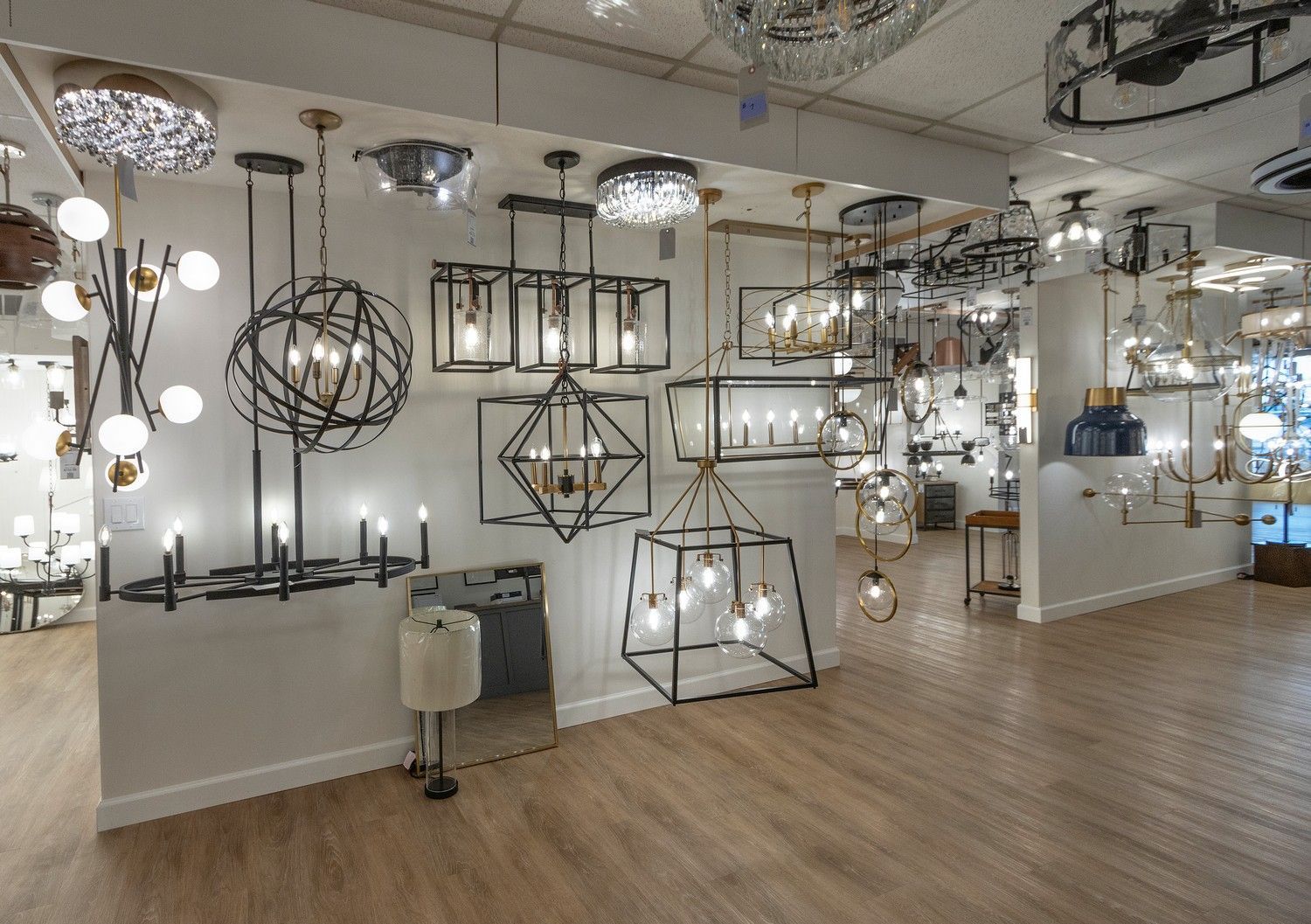 A showroom filled with modern hanging and floor lamps in a bright, open interior.