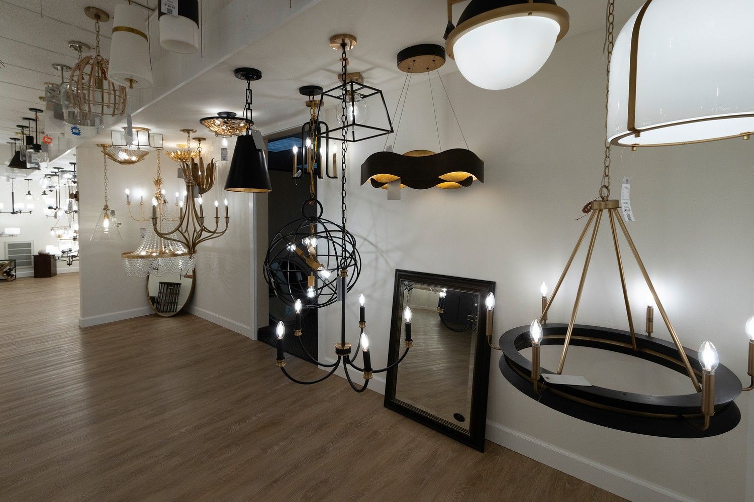 Showroom display of assorted hanging light fixtures and chandeliers in a white room.
