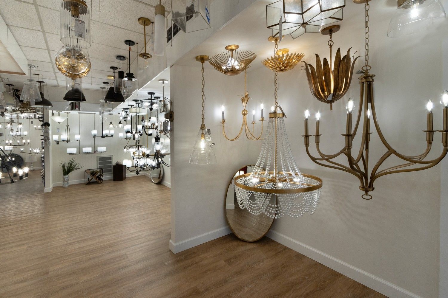 Showroom of decorative chandeliers and wall sconces with white walls and wood flooring