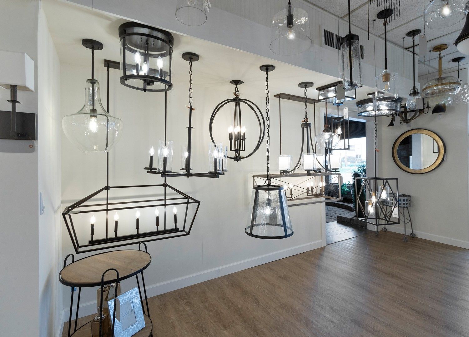 Bright modern lighting showroom with hanging pendant lamps and chandeliers over wood floors