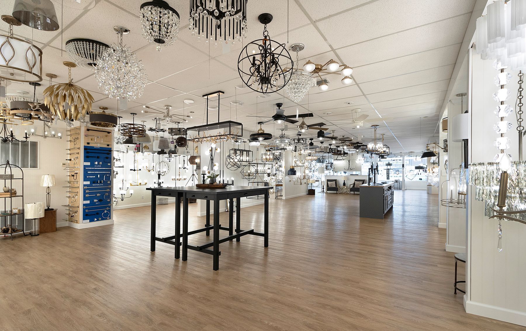 Bright lighting showroom with hanging lamps, display tables, and wood flooring