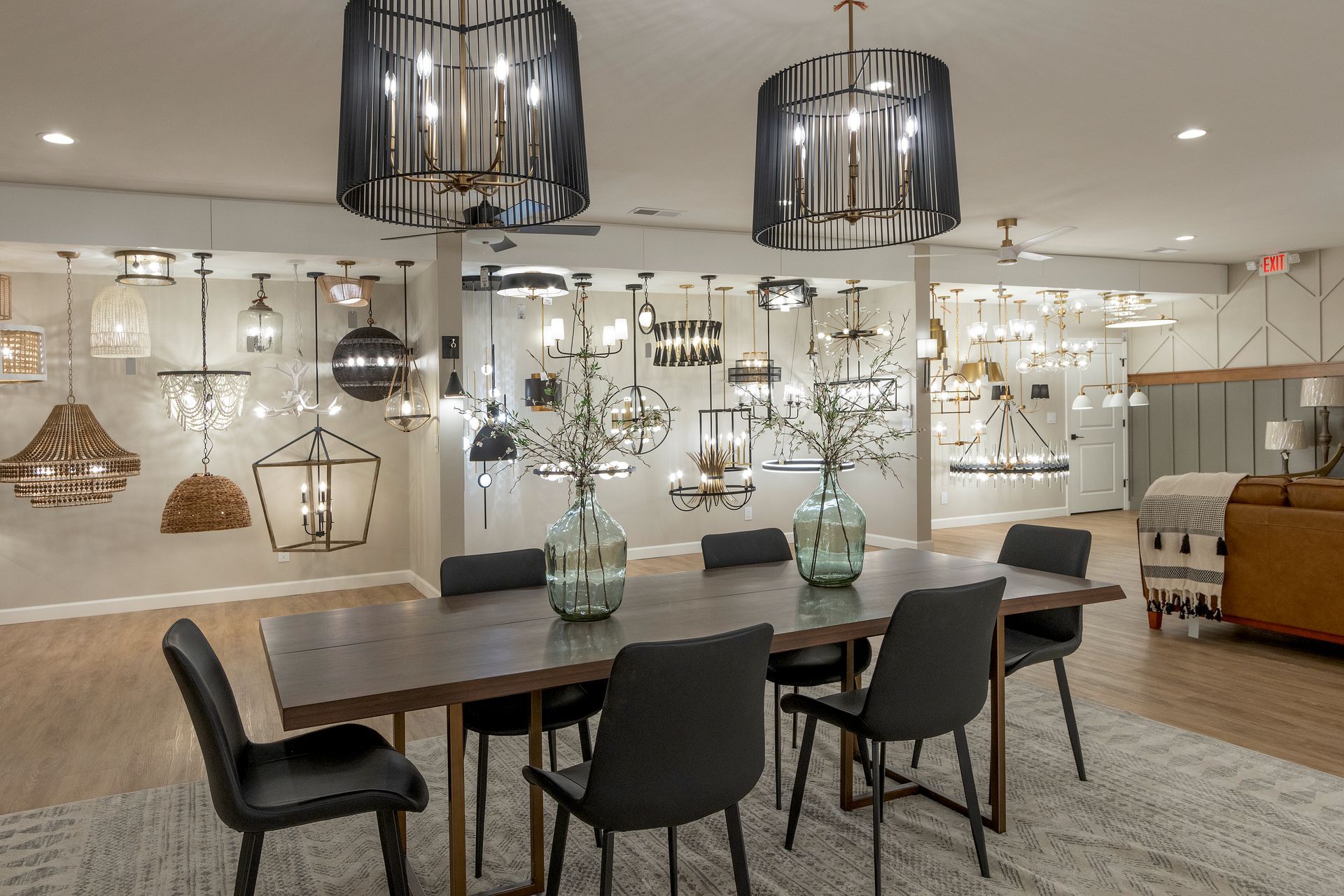 Modern dining showroom with pendant lights, wooden table, and upholstered chairs on a rug