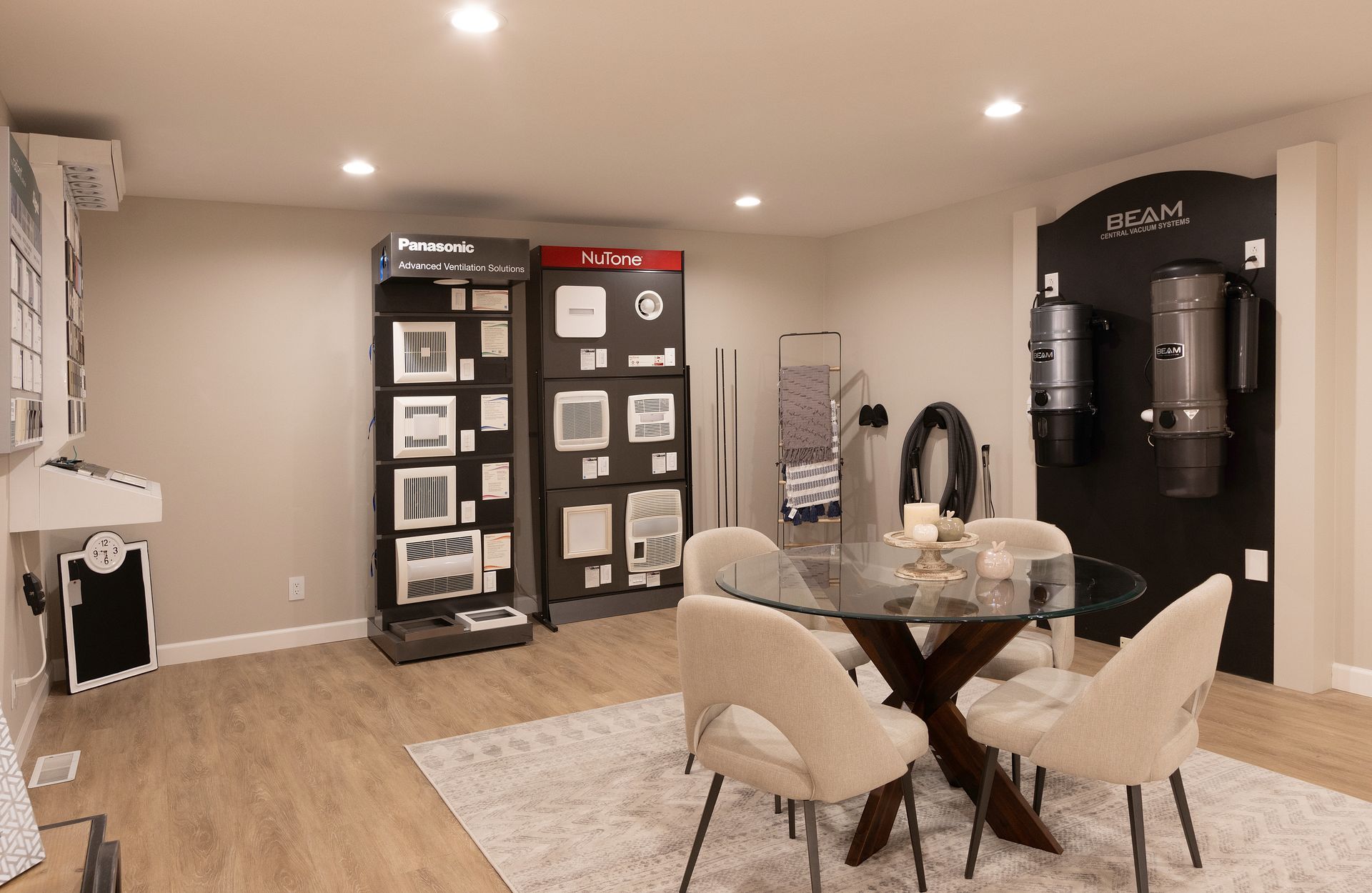 Modern dining room with a round table, beige chairs, display cabinets, and a coffee station on the right.