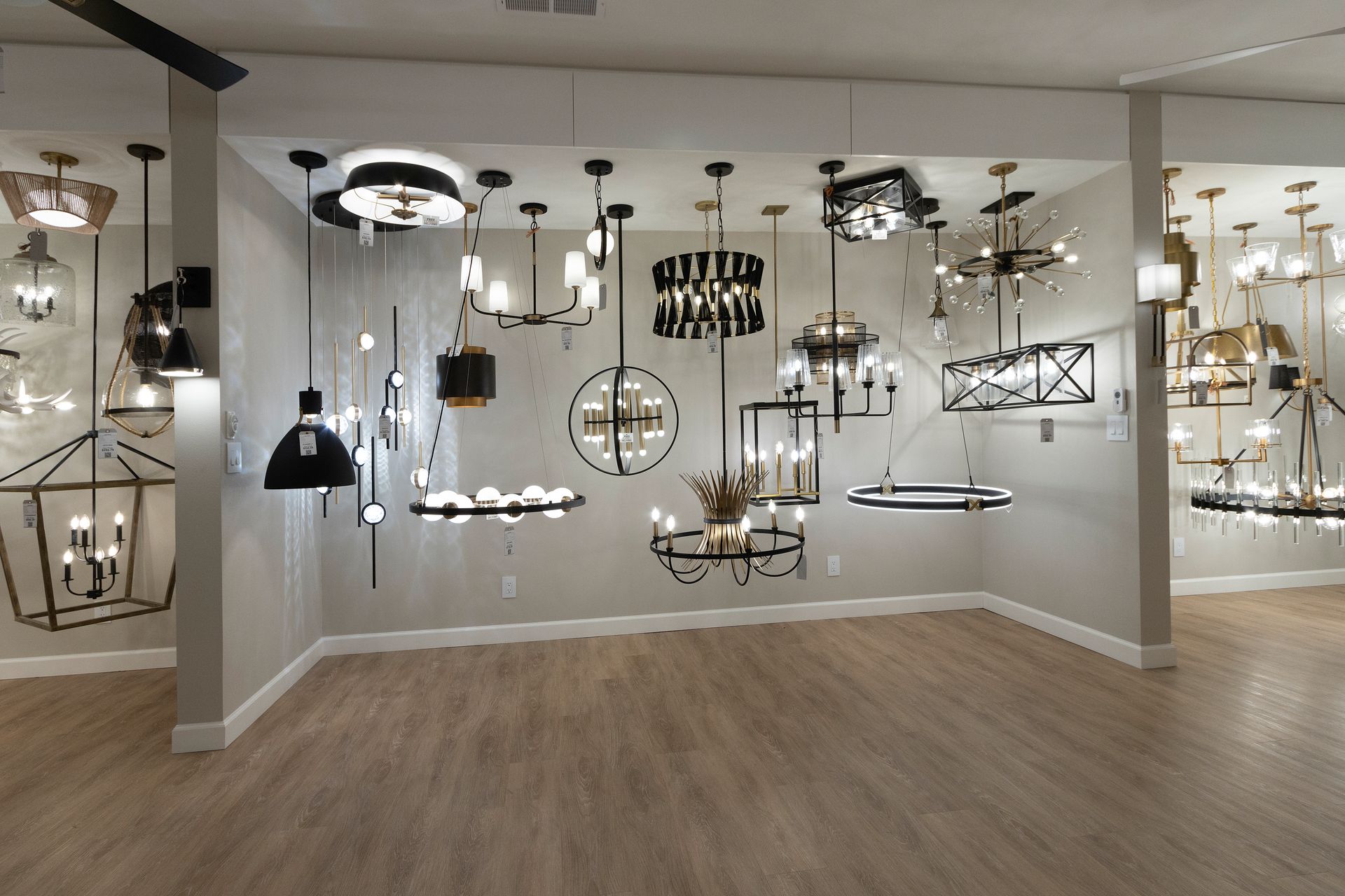 Showroom with many hanging light fixtures on display in a gray, wood-floored room