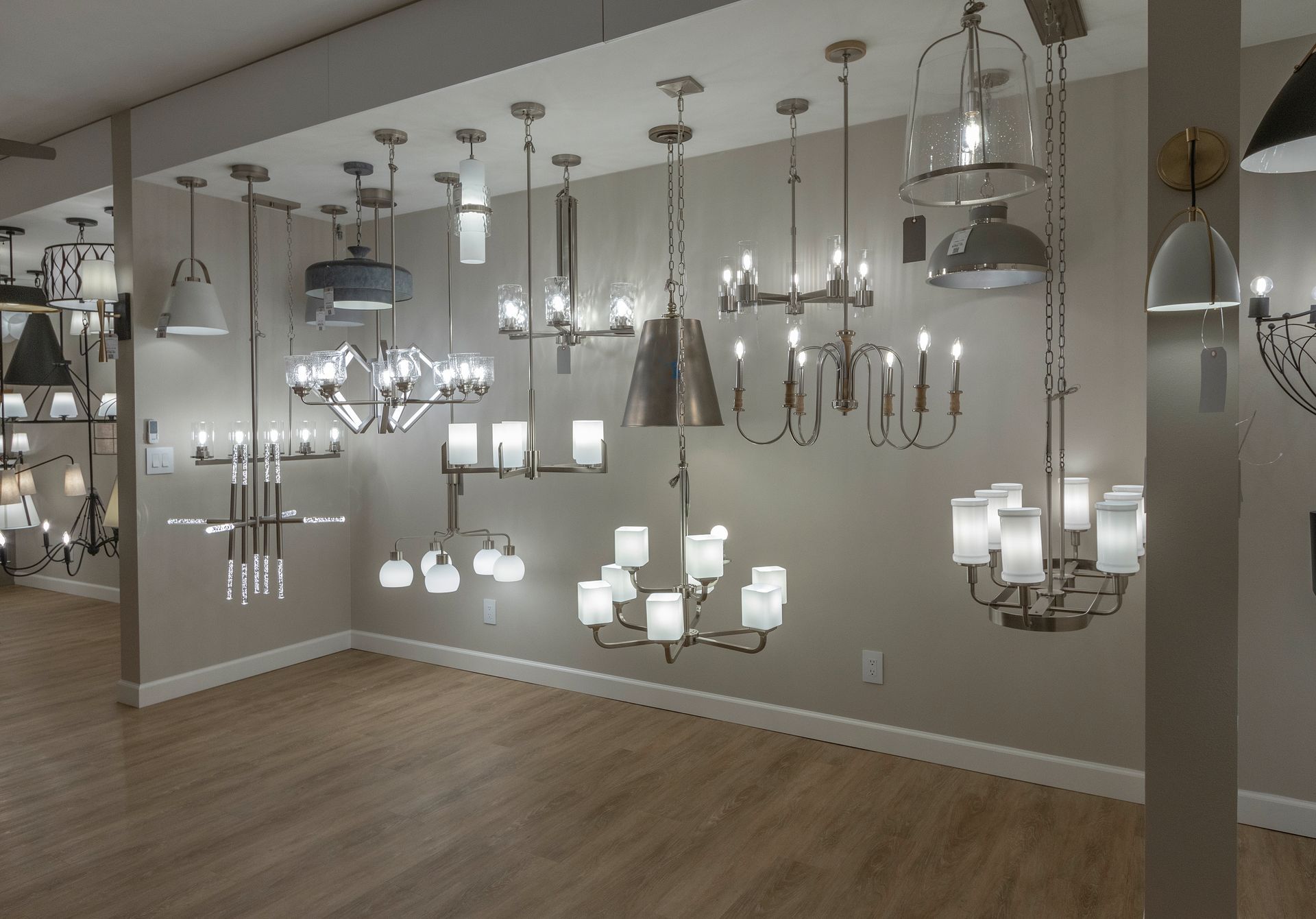 Lighting showroom with many hanging chandeliers and pendant lights in a neutral room