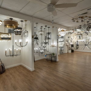 Lighting showroom with many hanging chandeliers and pendant lights in a spacious room with wood flooring