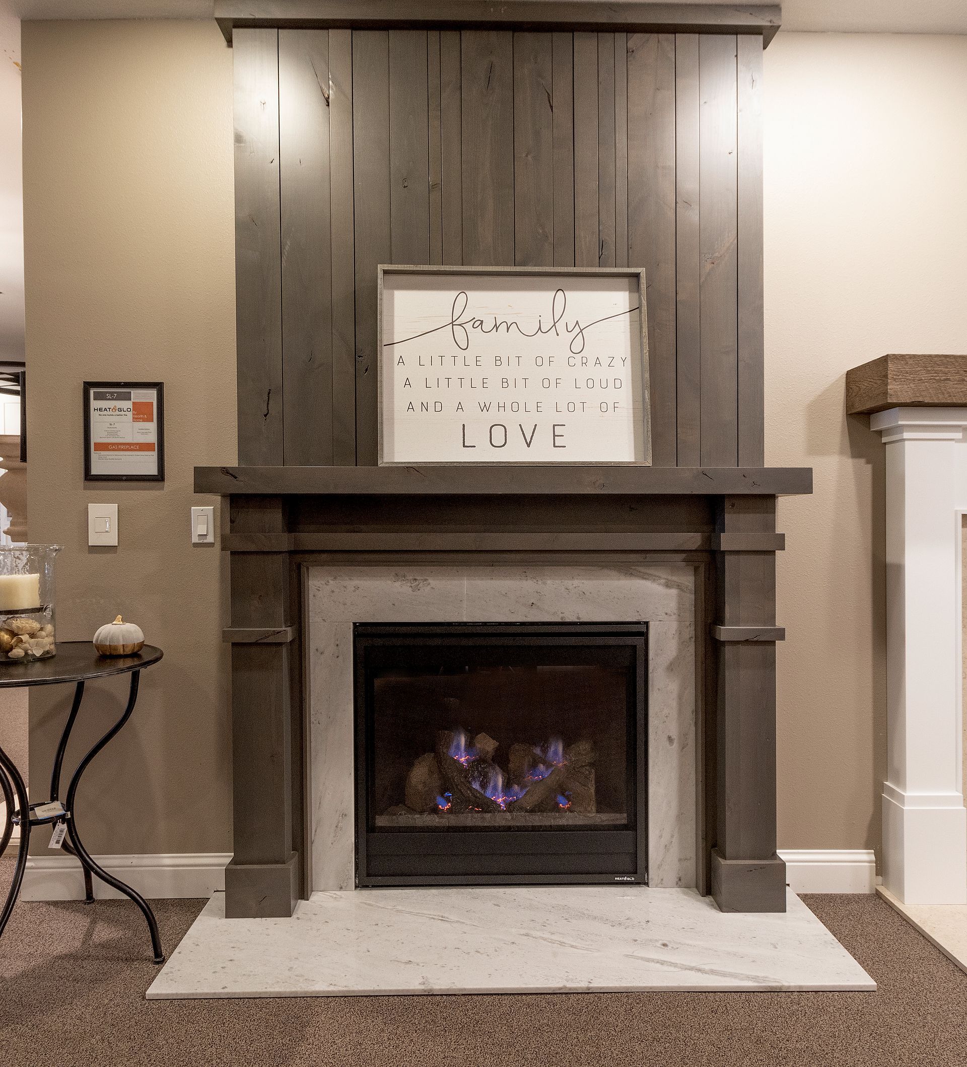 Living room fireplace with dark mantle, framed art, and a lit fire under a white surround