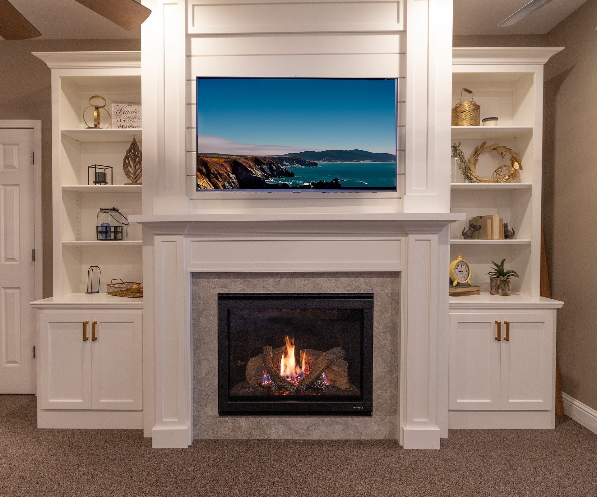 Built-in white shelving and a fireplace with a coastal TV display above it