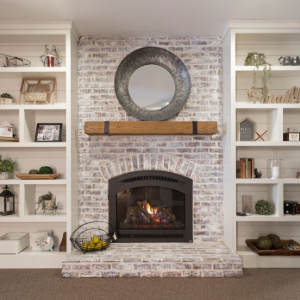 Living room fireplace with white built-in shelves, brick surround, and a round mirror above the mantel