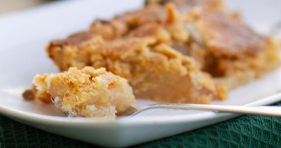 Close-up of a slice of crumbly peach pie on a white plate