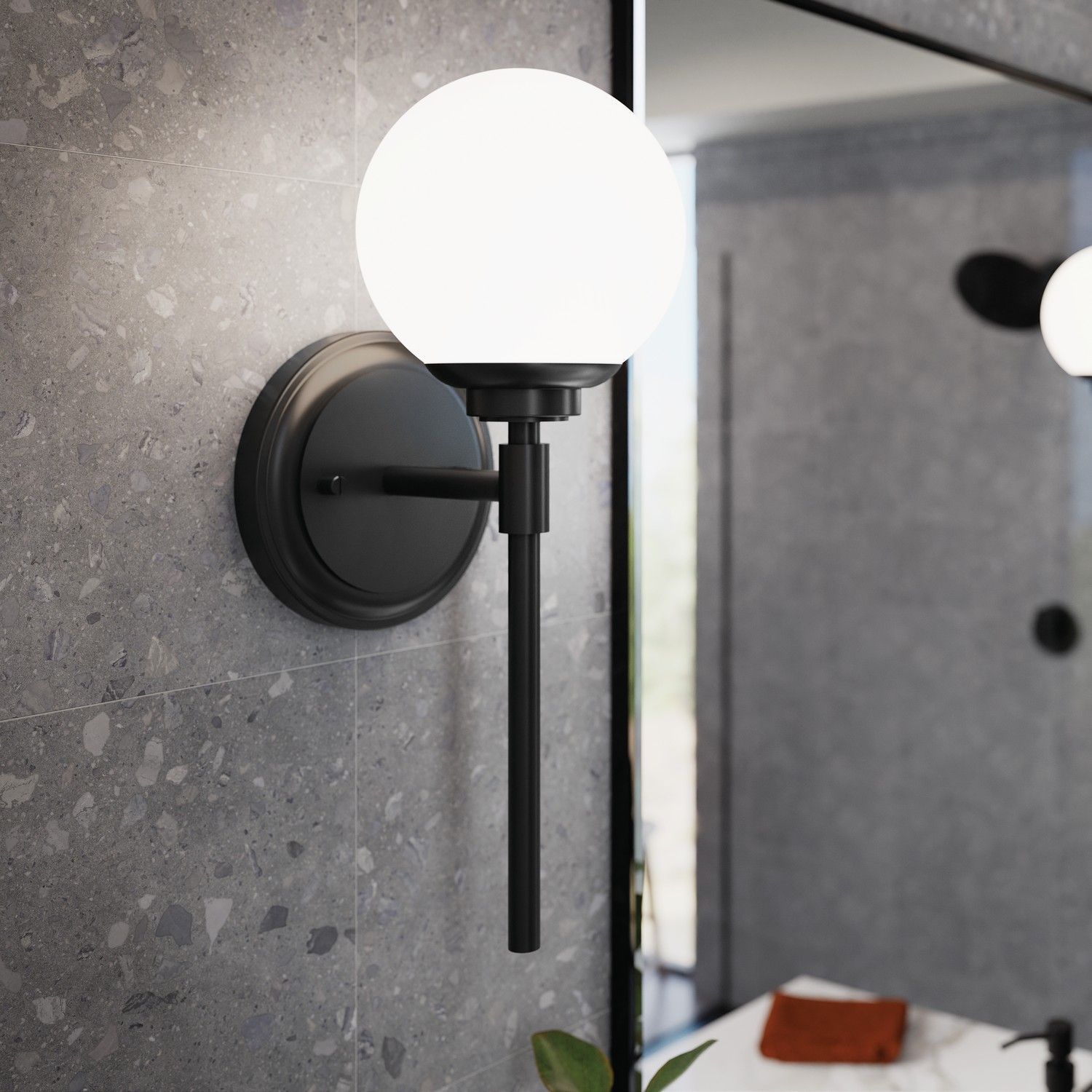 Black wall sconce with frosted globe light beside a bathroom mirror, with a hanging pull cord.