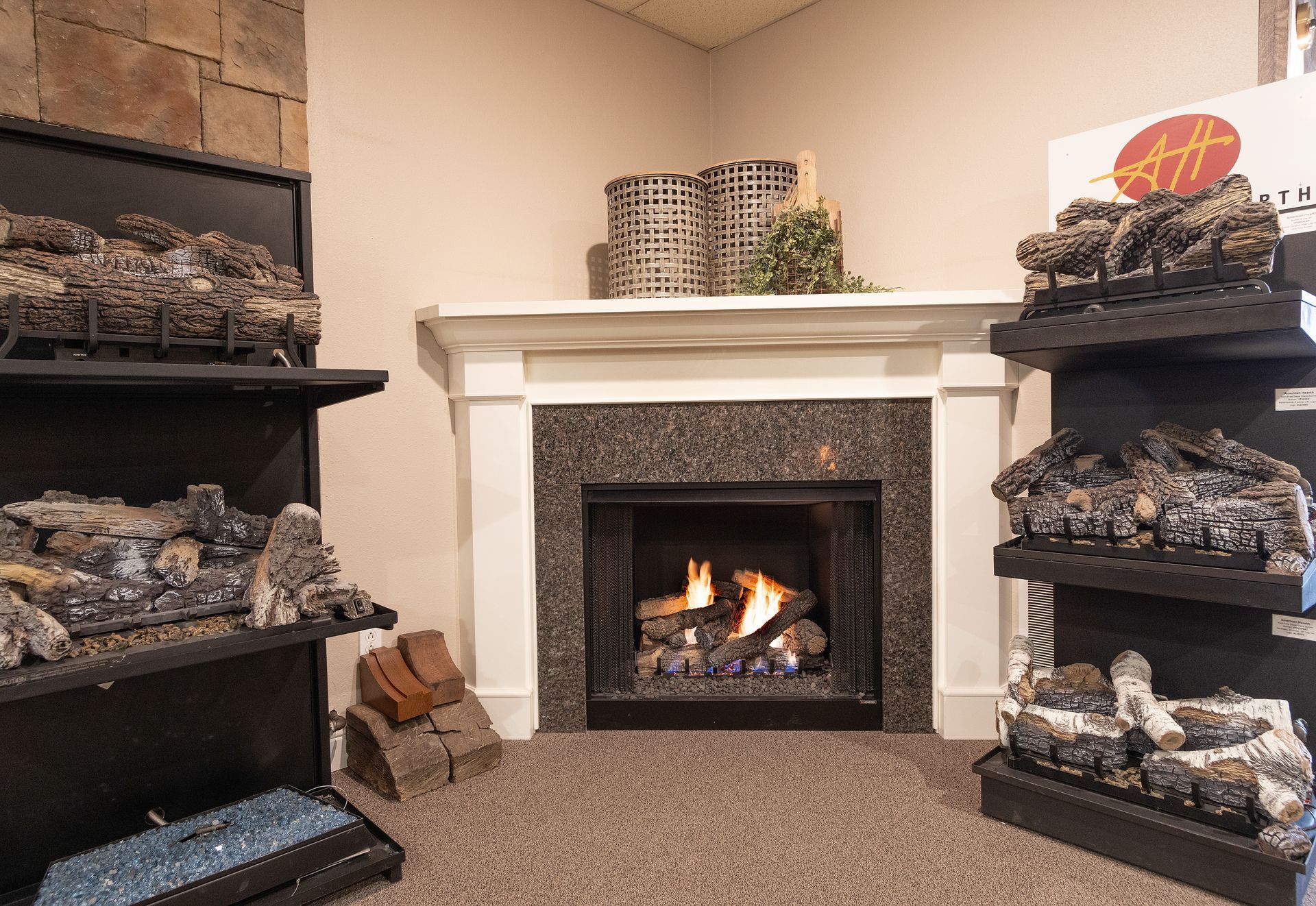 Cozy fireplace display with stacked logs on black shelves and a white mantel in a beige room