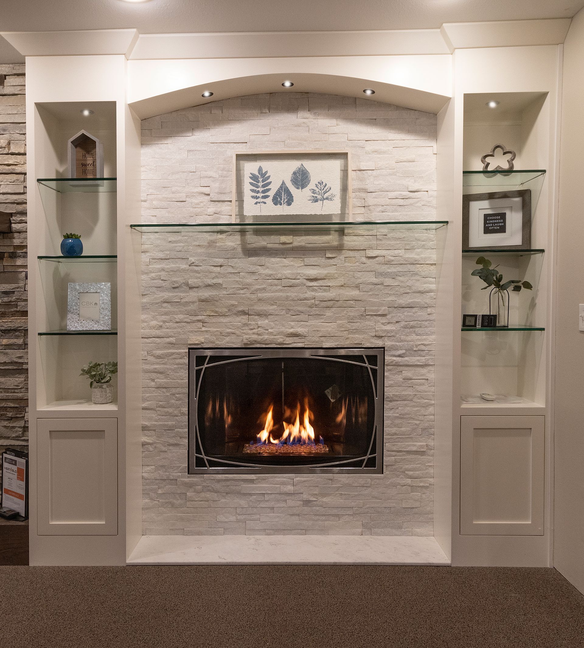 Built-in fireplace with lit fire, white brick surround, and glass shelves in a beige living room
