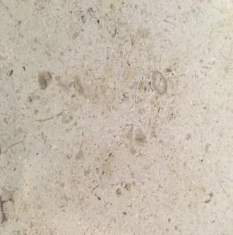 Close-up of a light beige speckled stone surface with faint marks and spots