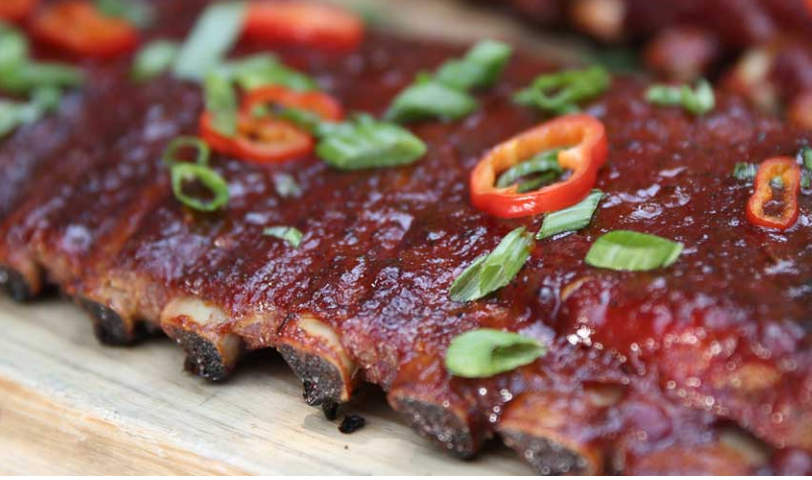 Barbecue ribs glazed with sauce and topped with sliced green onions and red peppers