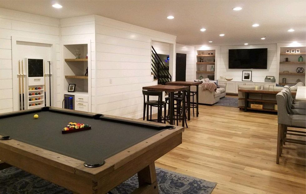 Open basement rec room with pool table, bar stools, sofa, and wall-mounted TV