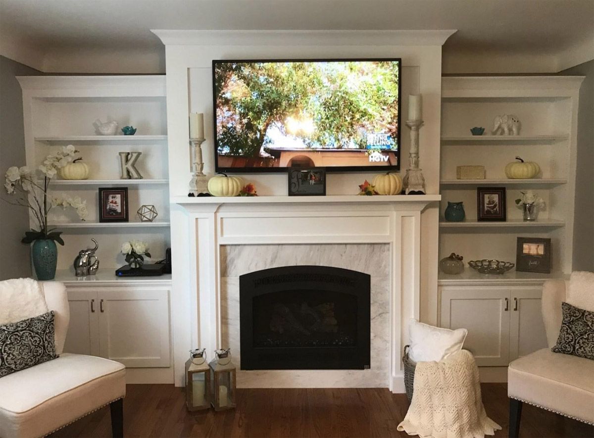 Living room with white built-in shelves, fireplace, and wall-mounted TV above the mantel