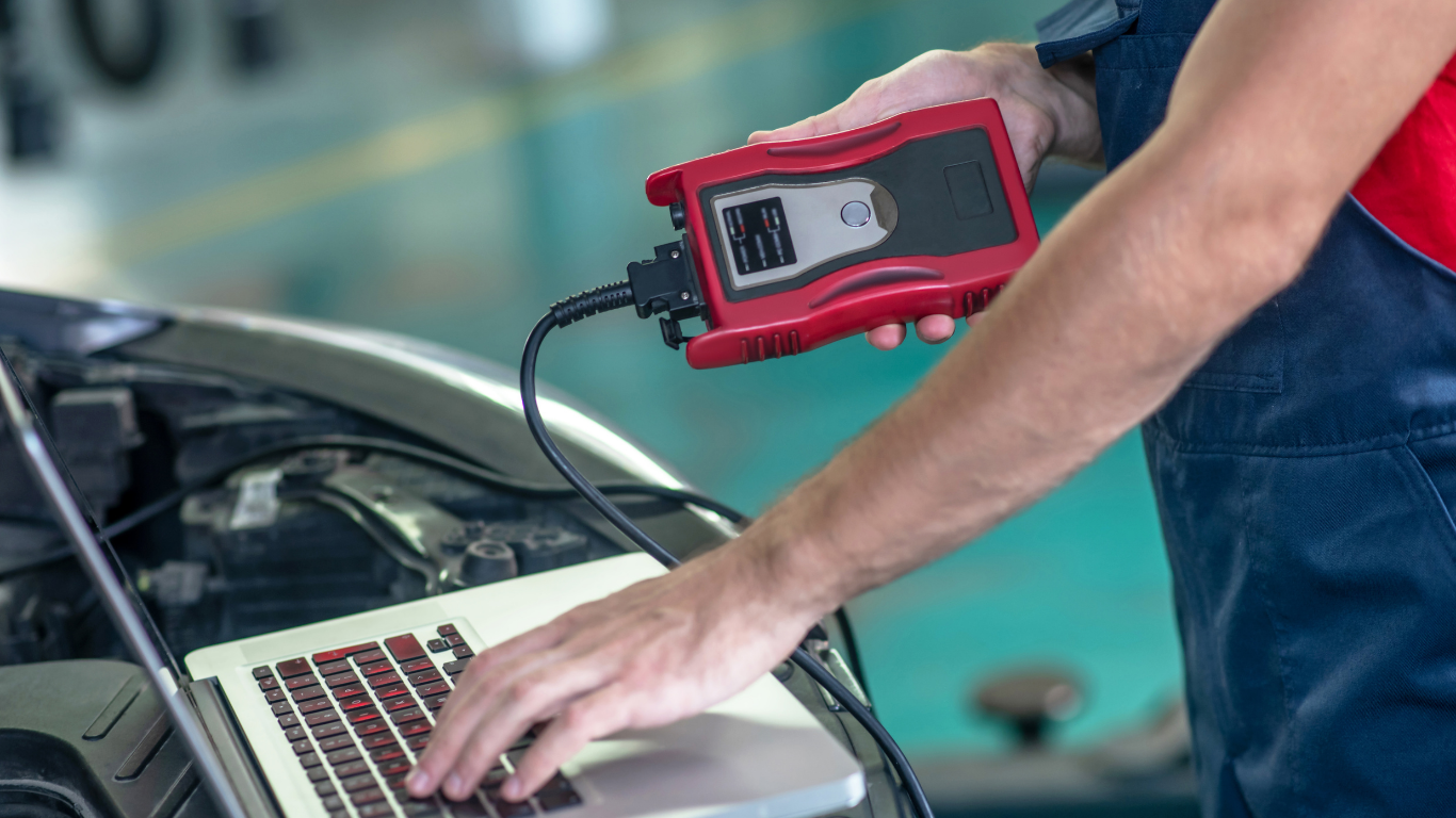 A mechanic is using a laptop computer to diagnose a car.