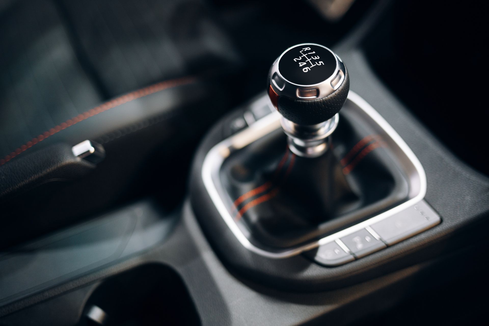 Close-up of a car’s manual gear shift knob and center console in a dark interior