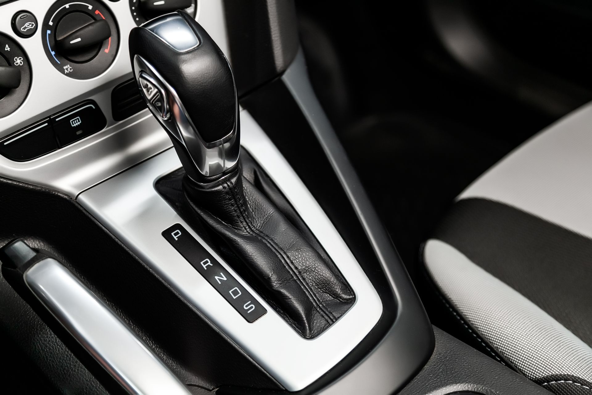Close-up of a car’s automatic gear shift and center console in black and silver.