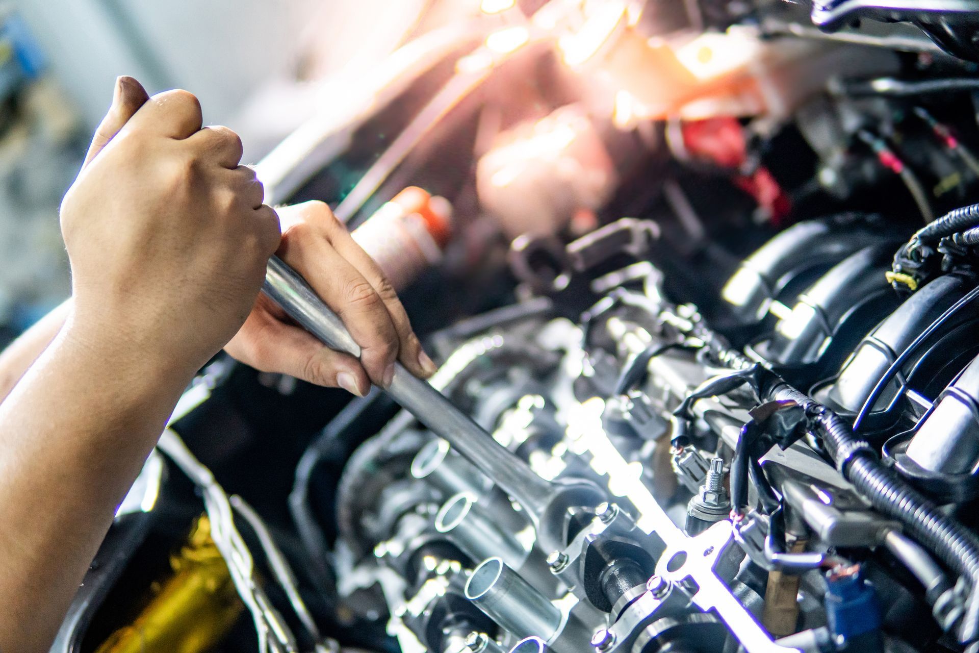 Mechanic using a wrench to repair a car engine in a garage