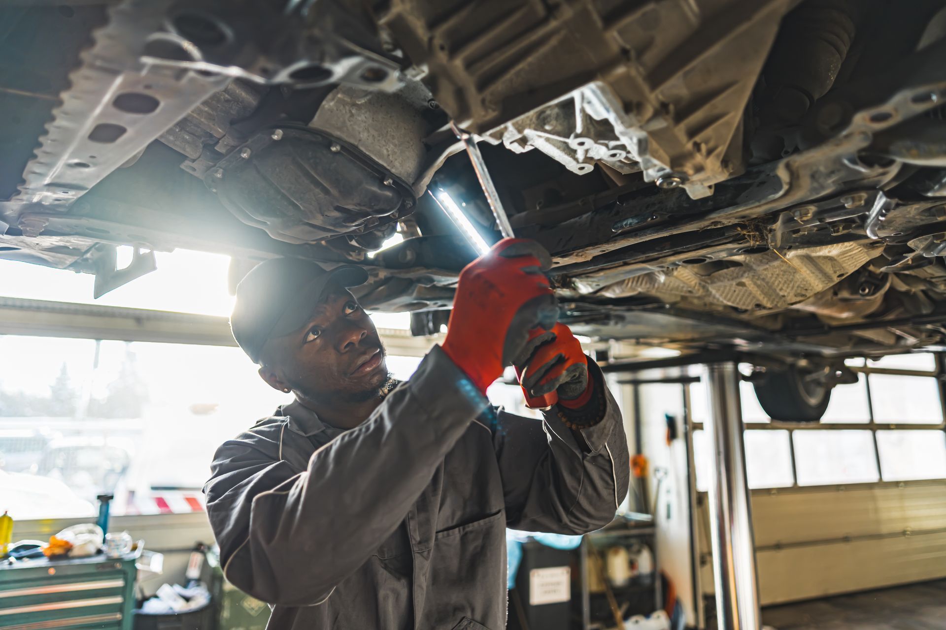 Mechanic using a wrench under a car on a lift in a garage